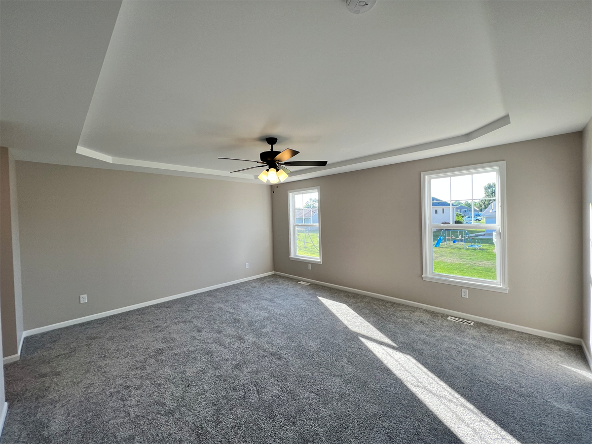 The Franklin master bedroom with ceiling fan and carpet
