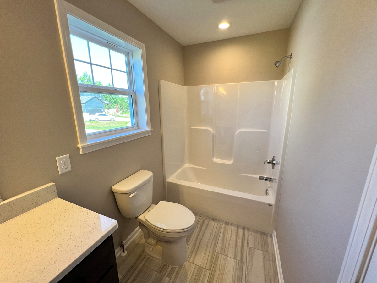 The Franklin main bathroom with ceramic floors, toilet and fiberglass shower