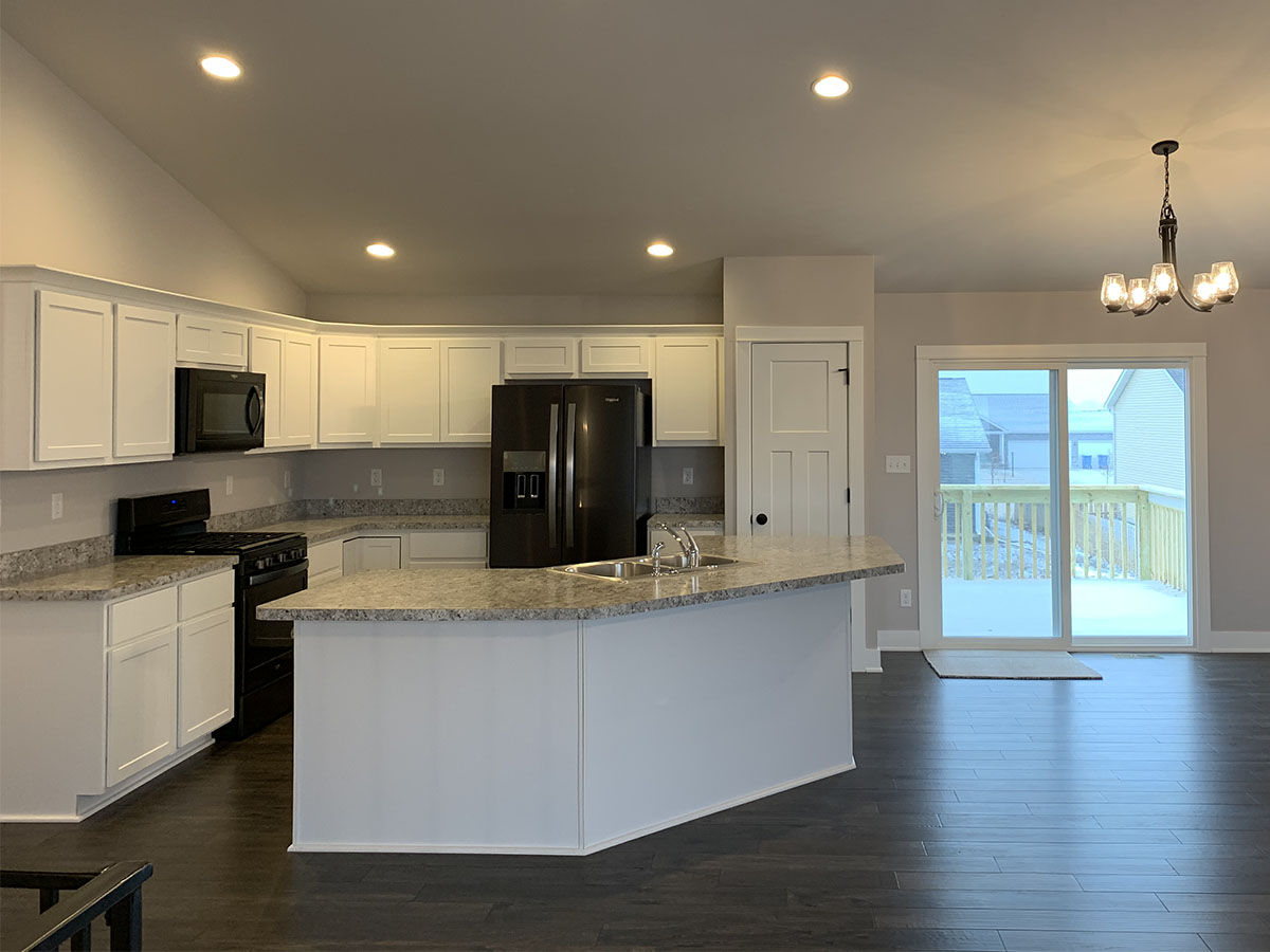 The Harrison kitchen with granite counter tops, white cabinets, and dark wood floor