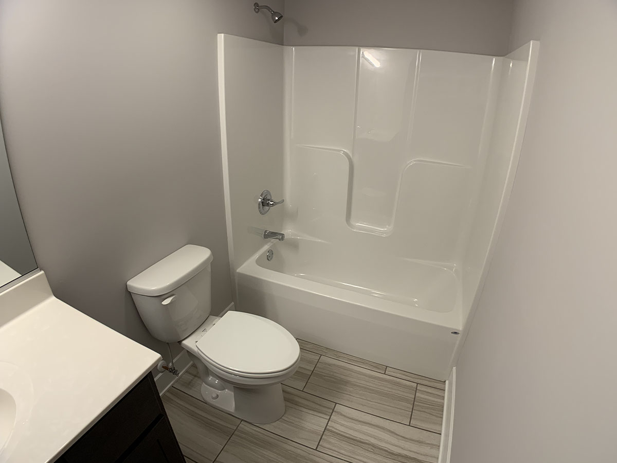 Lower level bathroom with sink, small mirror, tile floor, and shower