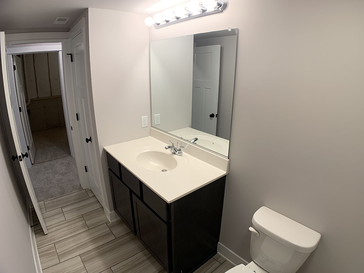 Lower level bathroom with sink, small mirror, tile floor, and shower