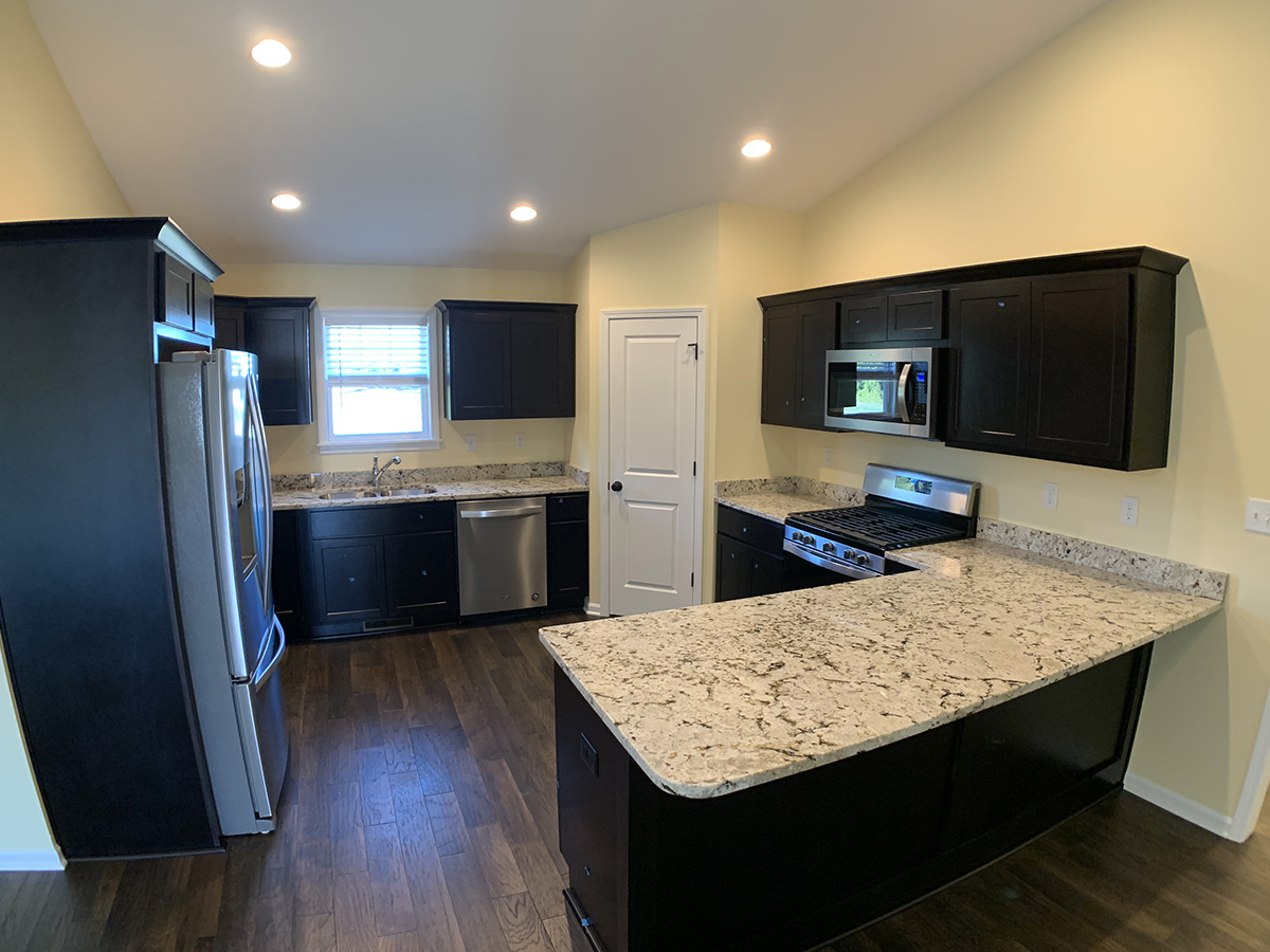 The Juniper kitchen with granite counter tops, dark cabinets, and dark wood floor