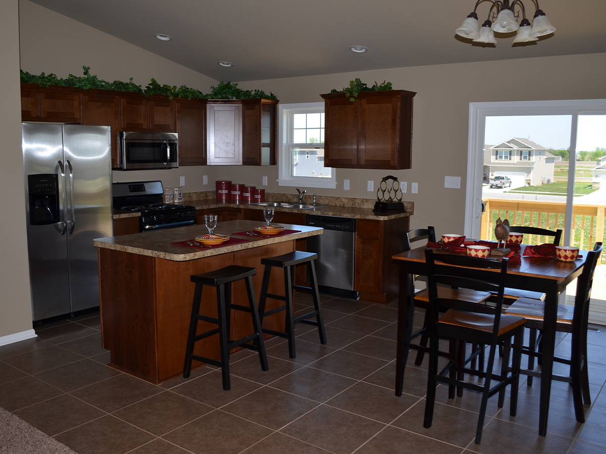 The Wolcott kitchen with granite counter tops, mahogany cabinets, and brown tile floor