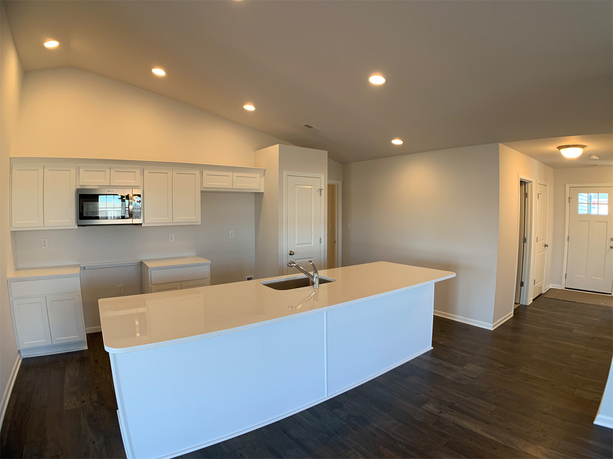 The Churchill kitchen with white cabinets, hardwood floors, kitchen island and appliances