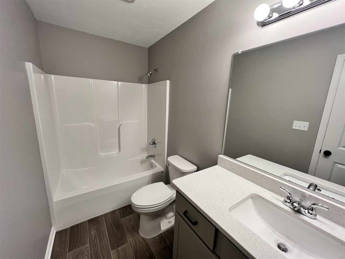 The Jefferson main bathroom with vanity, toilet and fiberglass shower
