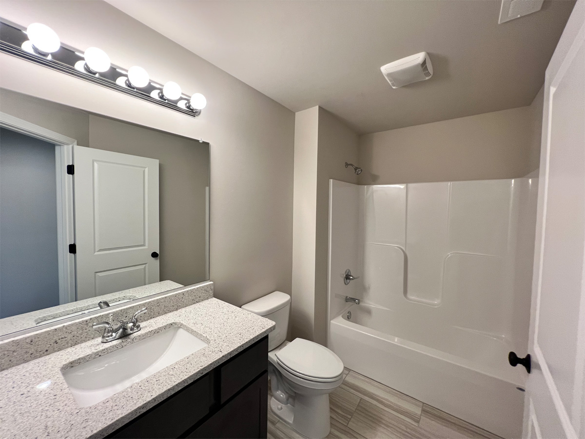 The Middleton main bathroom with vanity, toilet and fiberglass shower