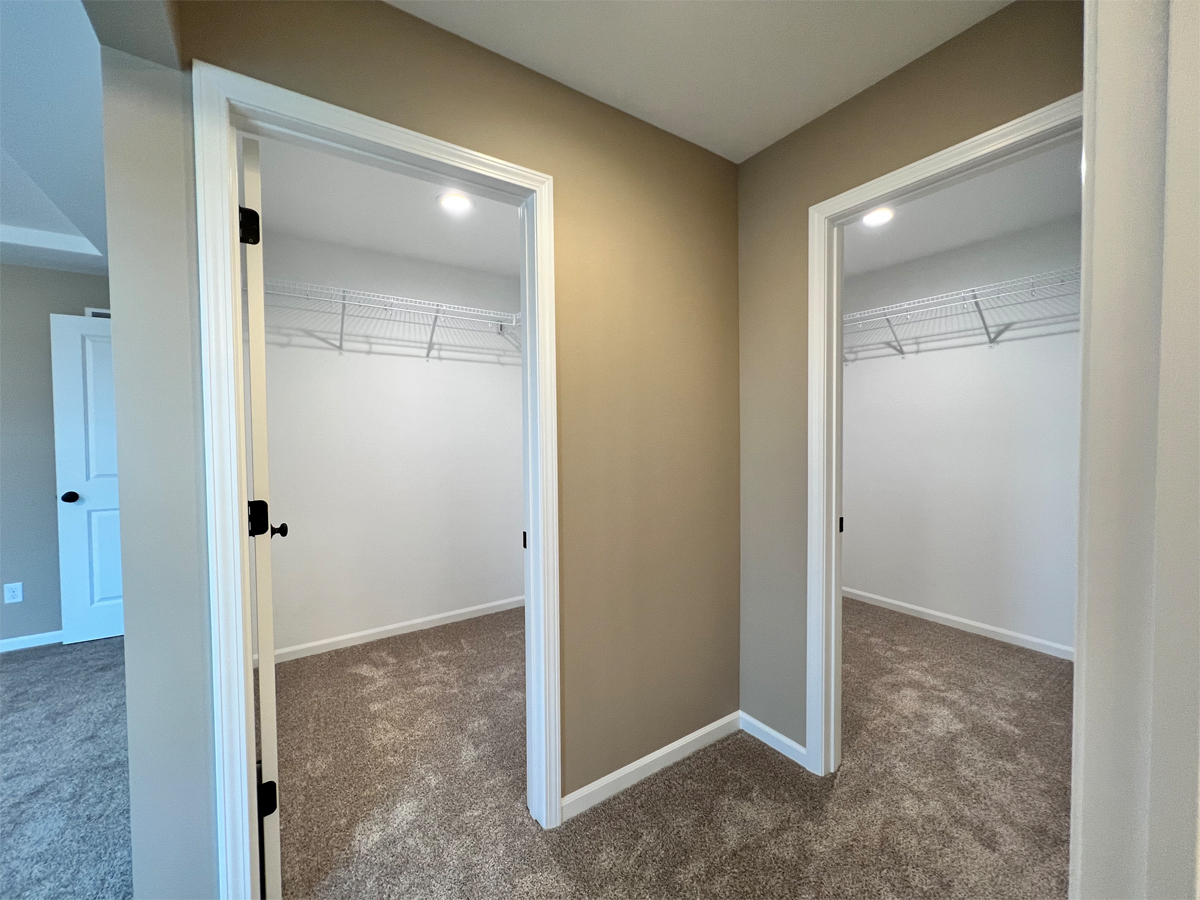 The Redbud master bedroom duel walk in closets with carpet and wire shelving