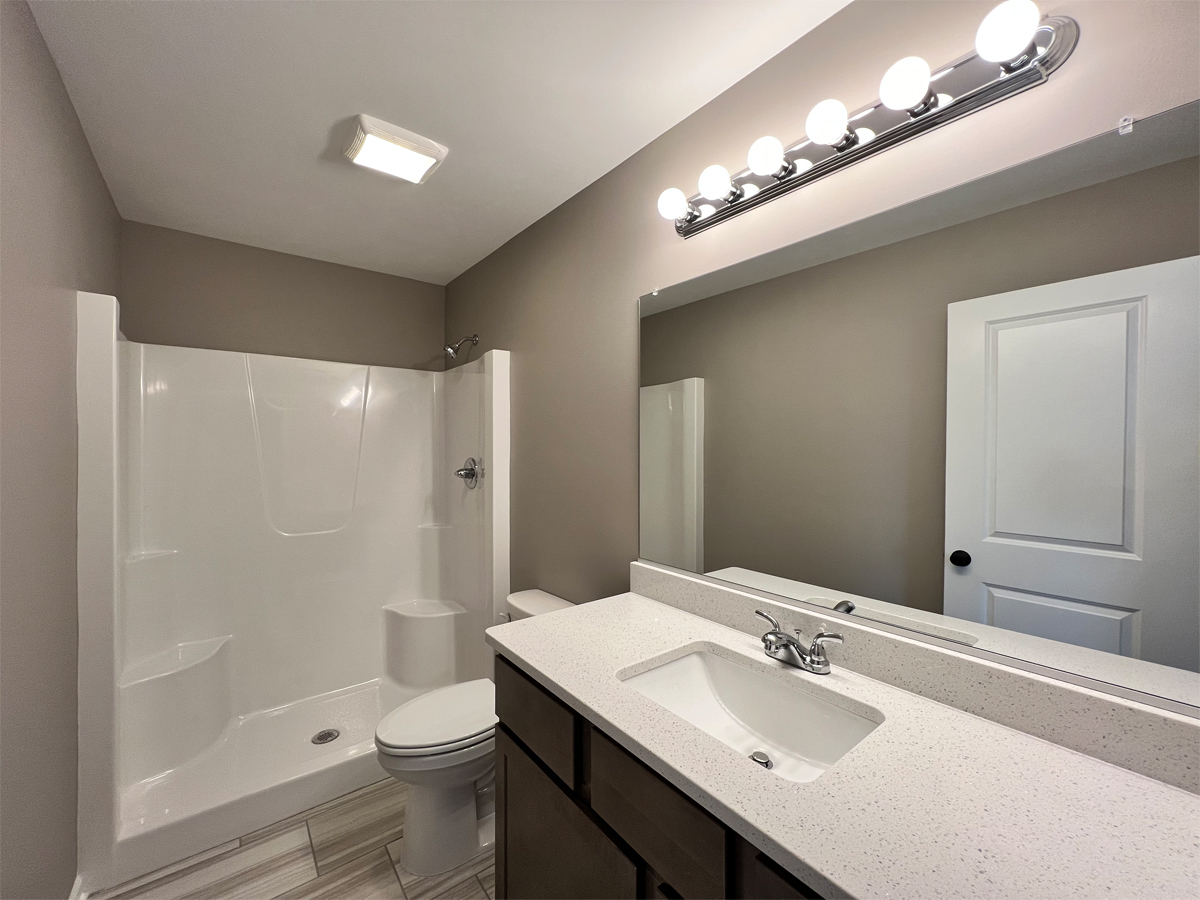 The Revere master bathroom with vanity, toiler and fiberglass shower