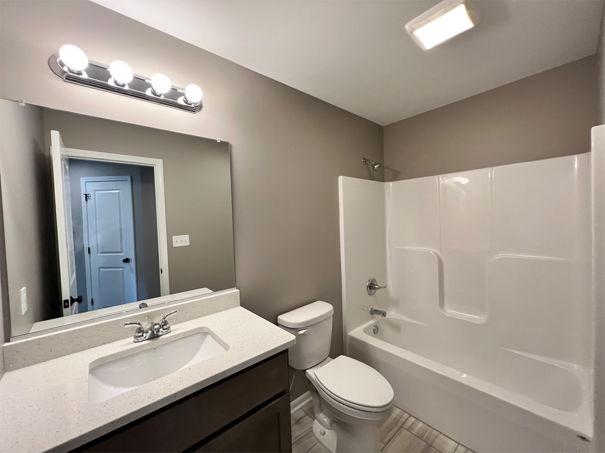 The Revere main bathroom with vanity, toilet and fiberglass shower