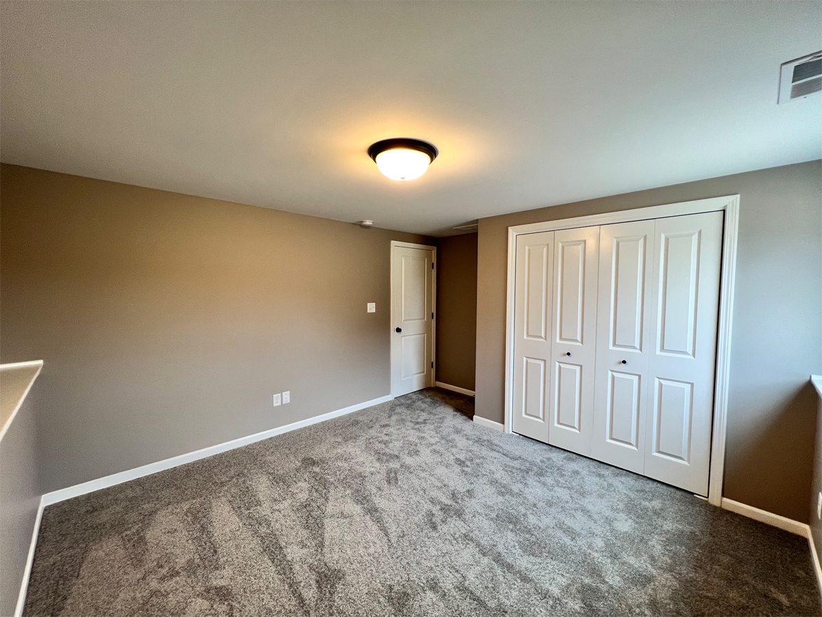 The Revere lower level bedroom with carpet and closet entry