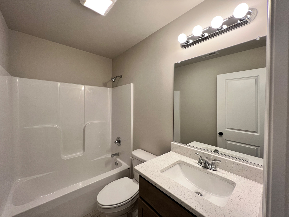 The Washington upper level bathroom with vanity, toilet and fiberglass shower