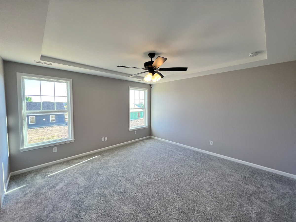 The Adams master bedroom with windows, carpet and ceiling fan