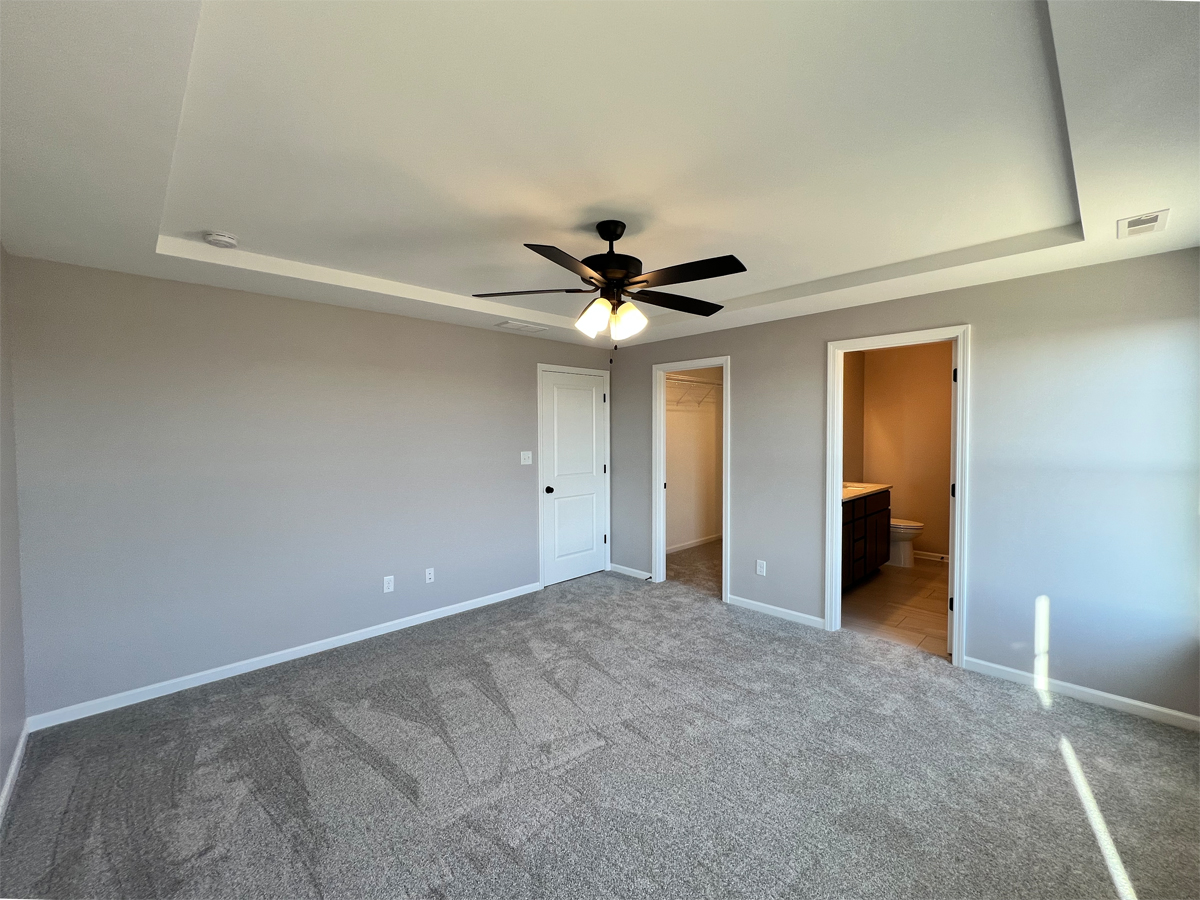 The Adams master bedroom with carpet, ceiling fan and entry to closet and master bathroom