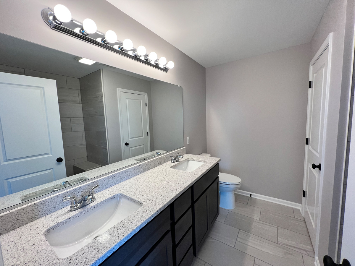 The Adams master bathroom with vanity, countertops, ceramic tile and toilet