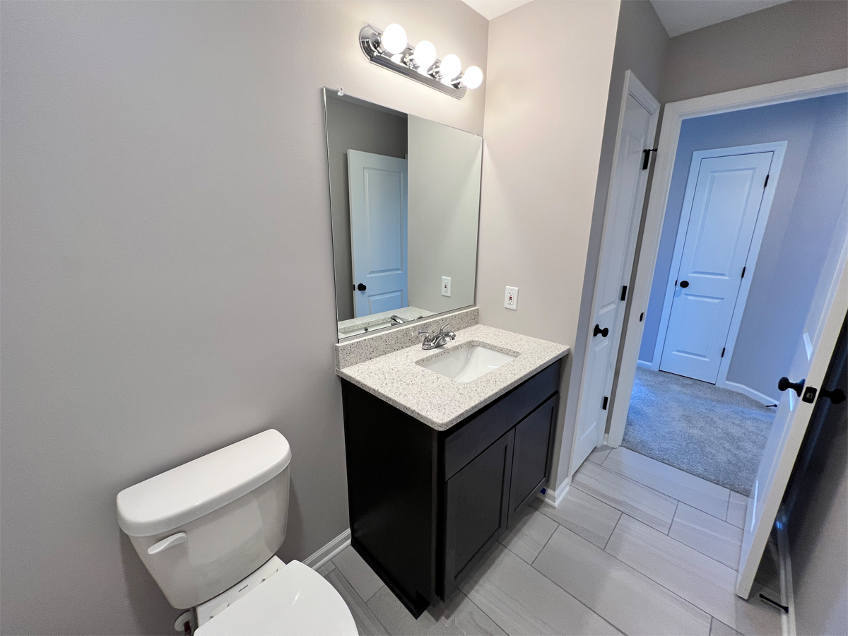 The Adams main bathroom with vanity, toilet and ceramic floors