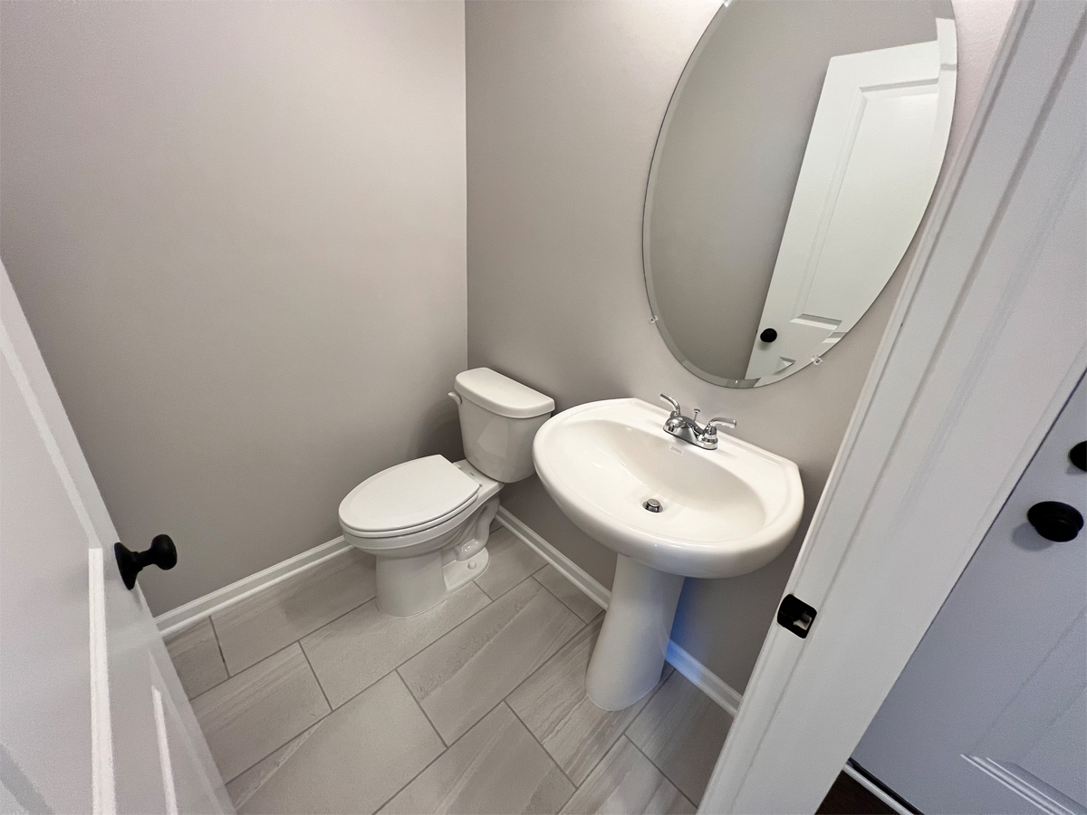 The Adams powder room with ceramic floors, toilet, sink and mirror