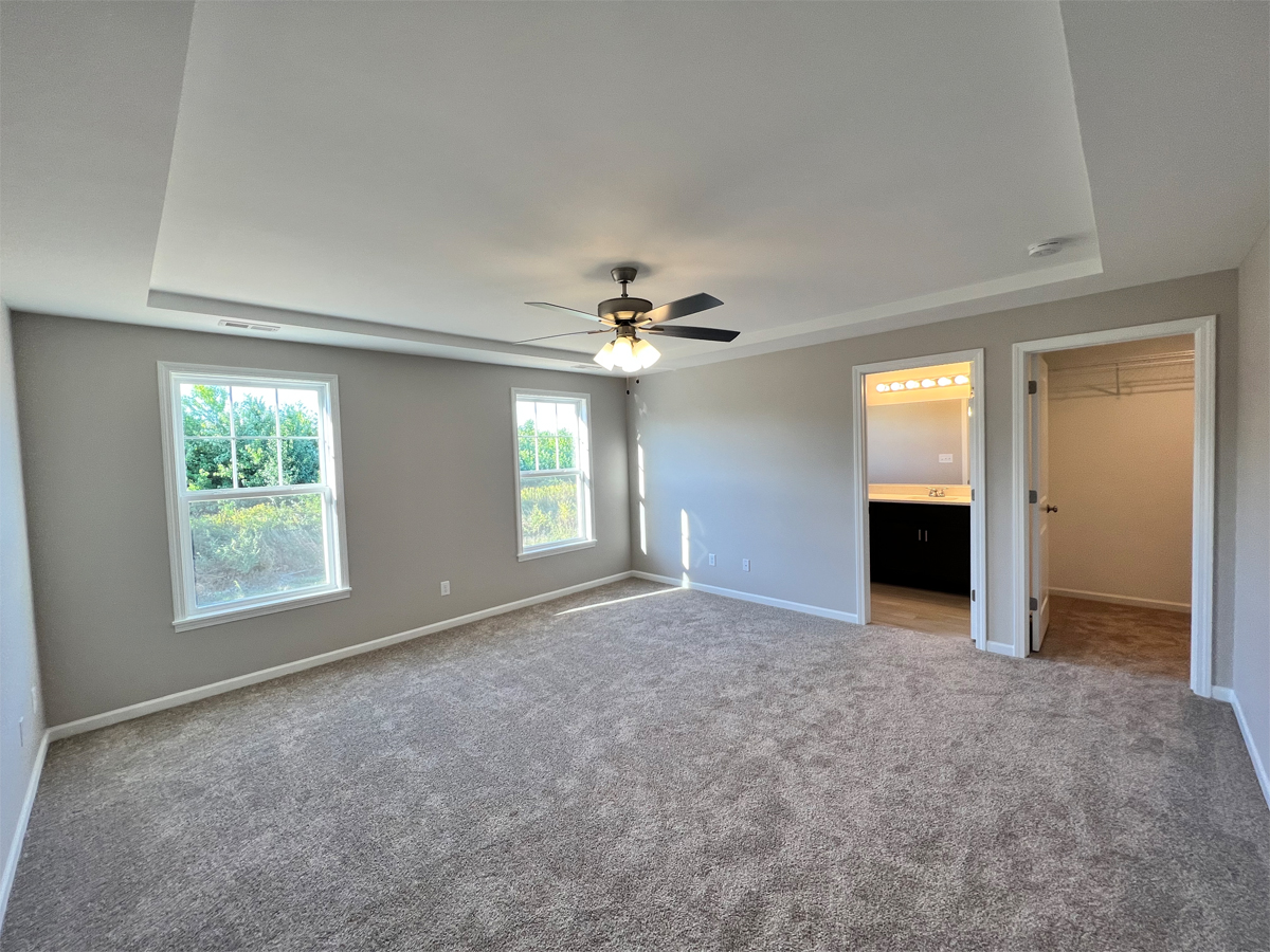 The Sherman master bedroom with ceiling fan and carpet