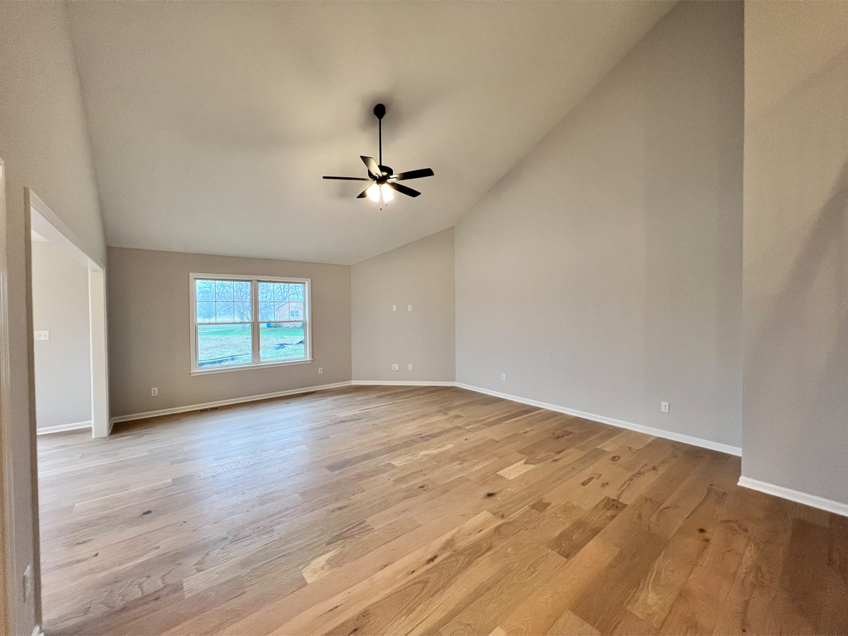 The Walton living room with ceiling fan and hardwood floors